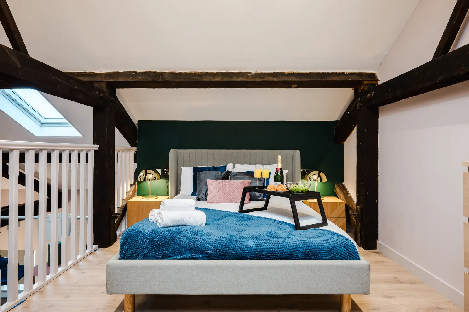 Character stock consistently premiums against generic new-build. Photography and pricing then determine how much of that premium reaches the landlord. Central Manchester serviced apartment loft bedroom with skylight and exposed beams
